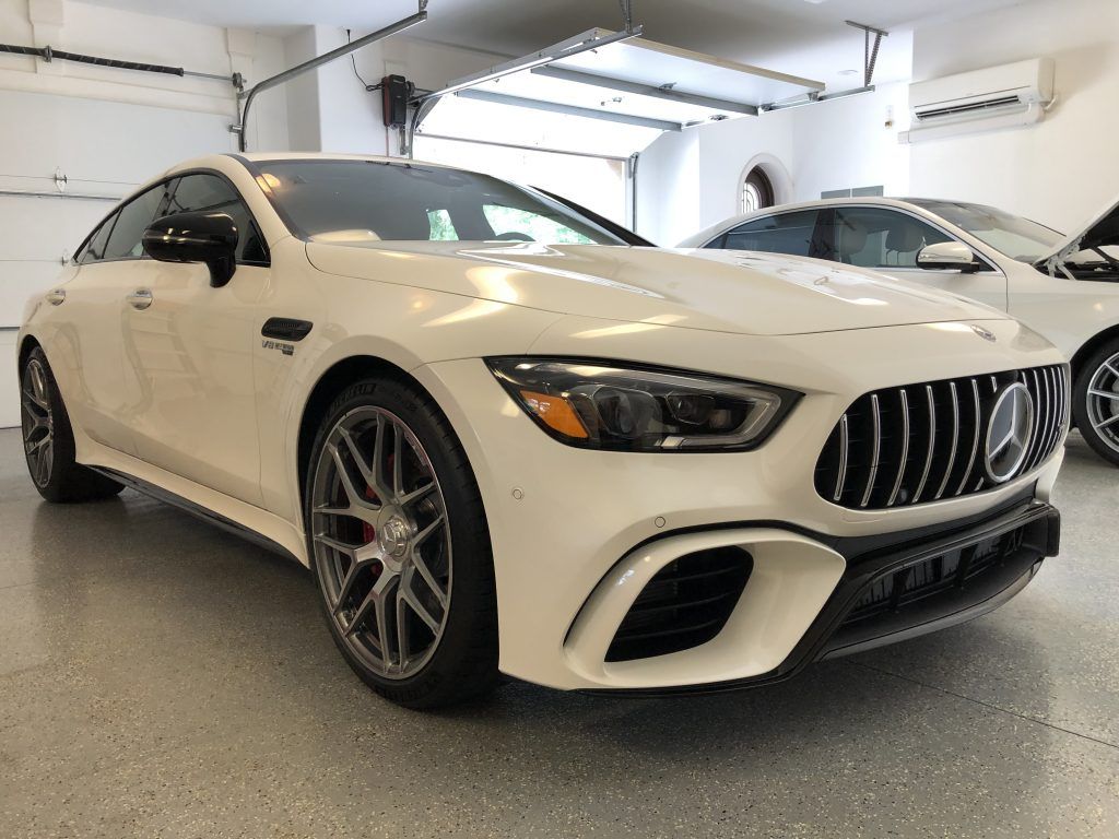 A white mercedes amg gt 63 s is parked in a garage.