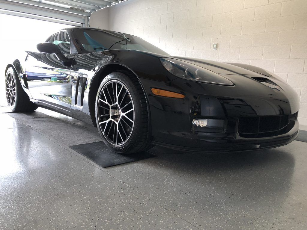 A black sports car is parked in a garage.