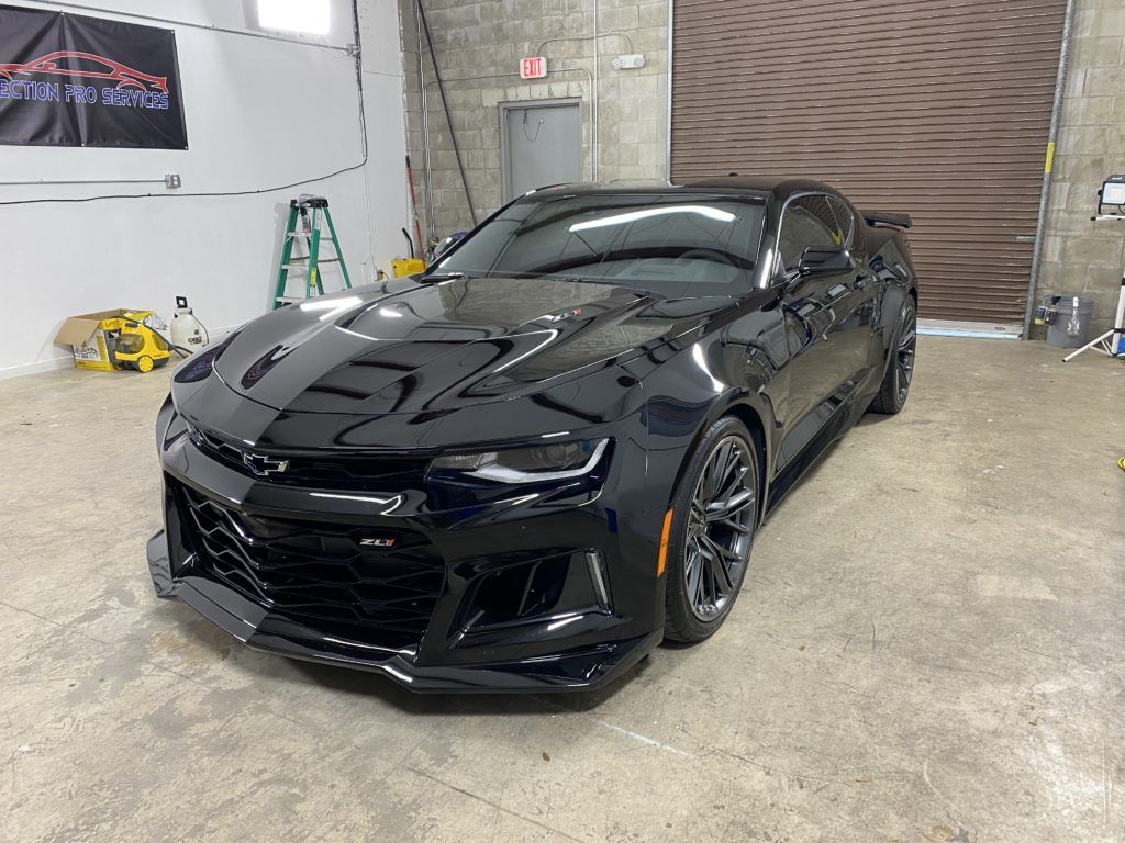 A black chevrolet camaro zl1 is parked in a garage.