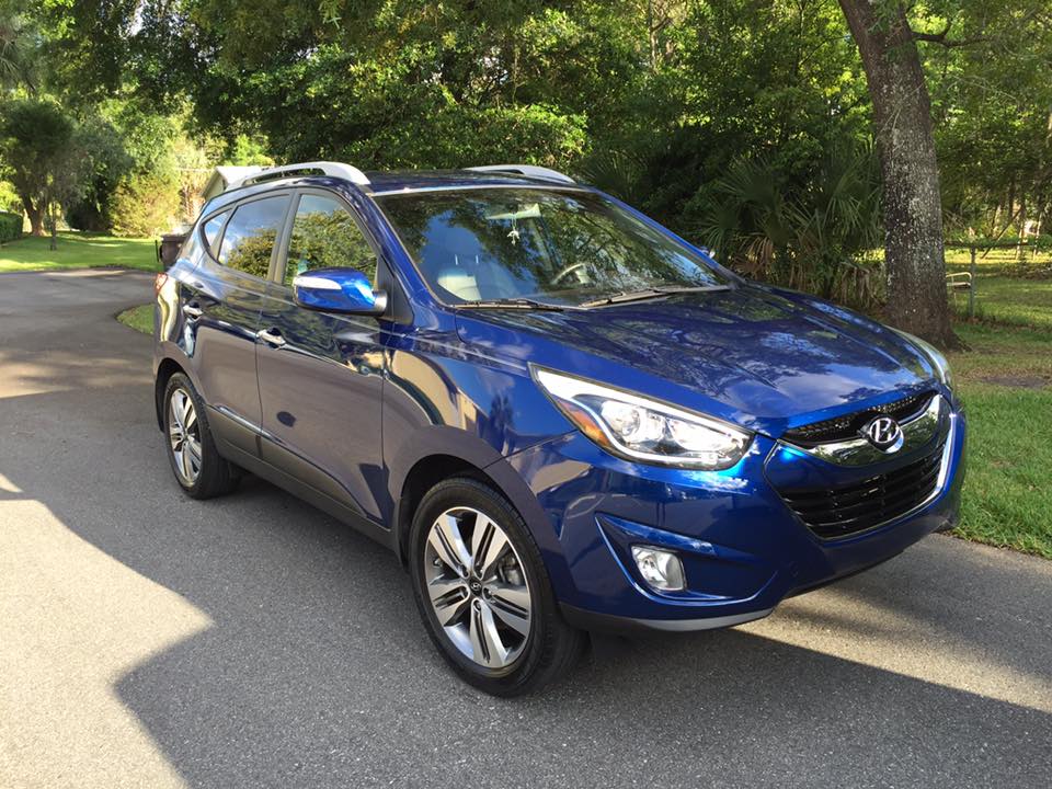 A blue hyundai tucson is parked on the side of the road.