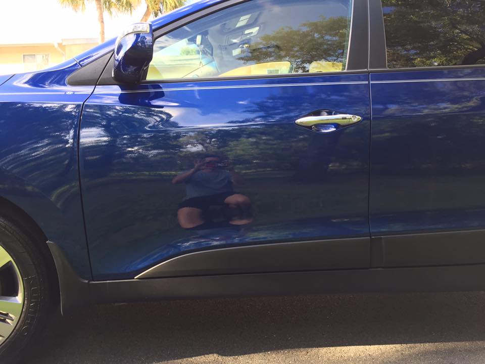 A blue car is parked on the side of the road