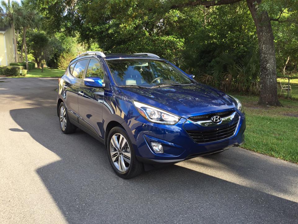 A blue hyundai tucson is parked on the side of the road.