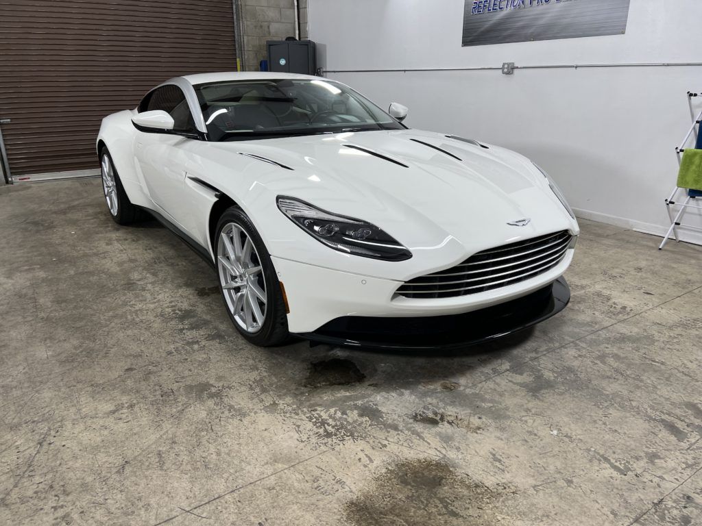 A white aston martin db11 is parked in a garage.