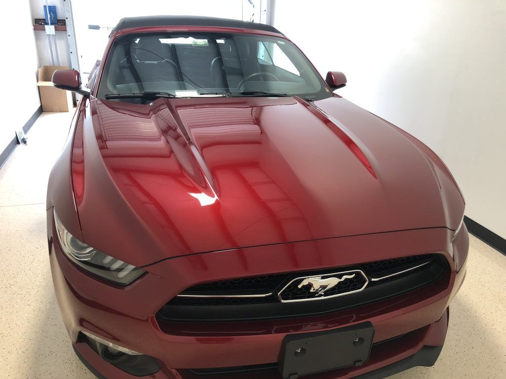 A red ford mustang is parked in a garage