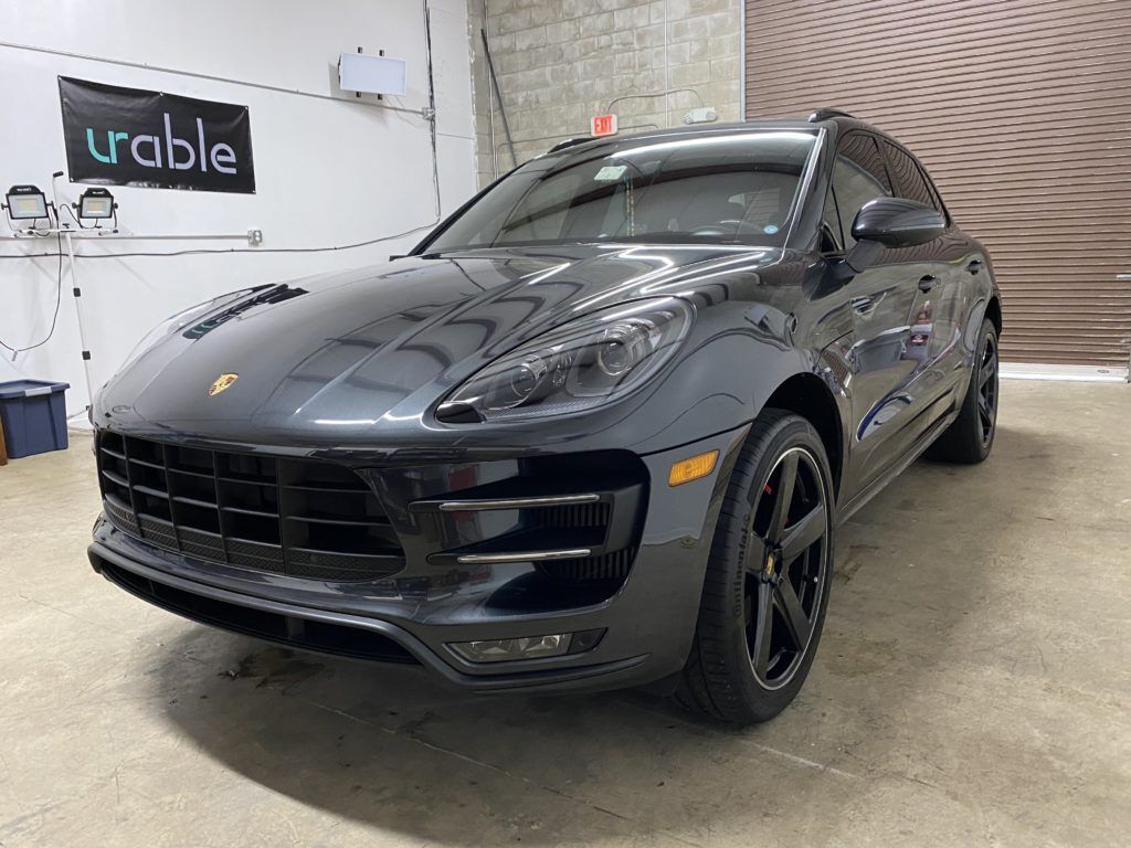 A black porsche macan turbo is parked in a garage.
