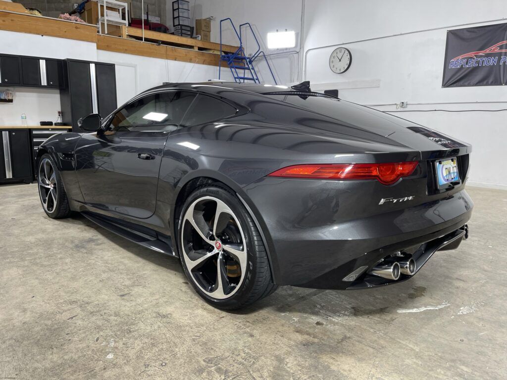 A black jaguar f type is parked in a garage.