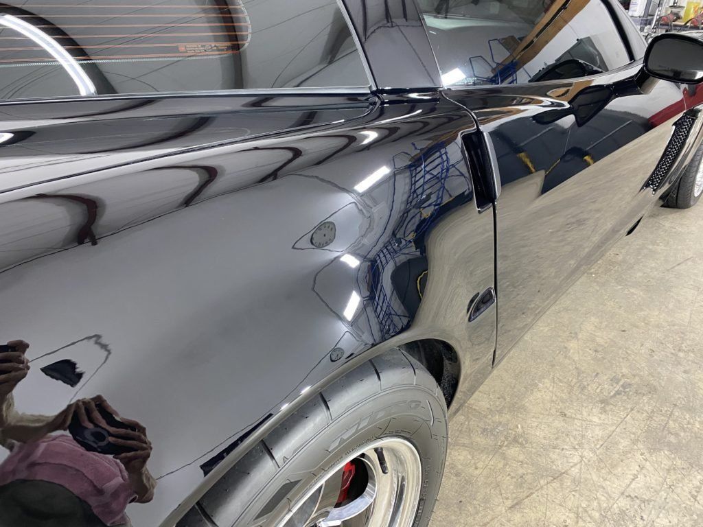 A black car is sitting on a cement floor in a garage.