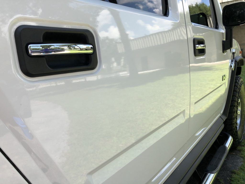 A white hummer h2 is parked on the side of the road.