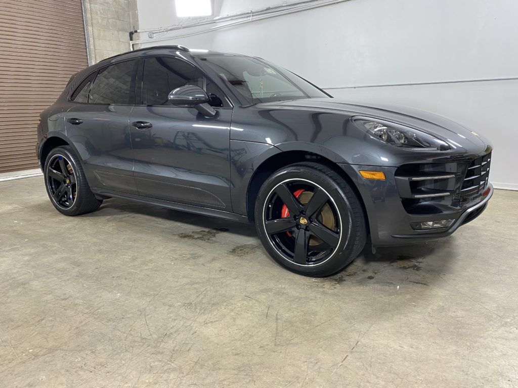 A black porsche macan turbo is parked in a garage.