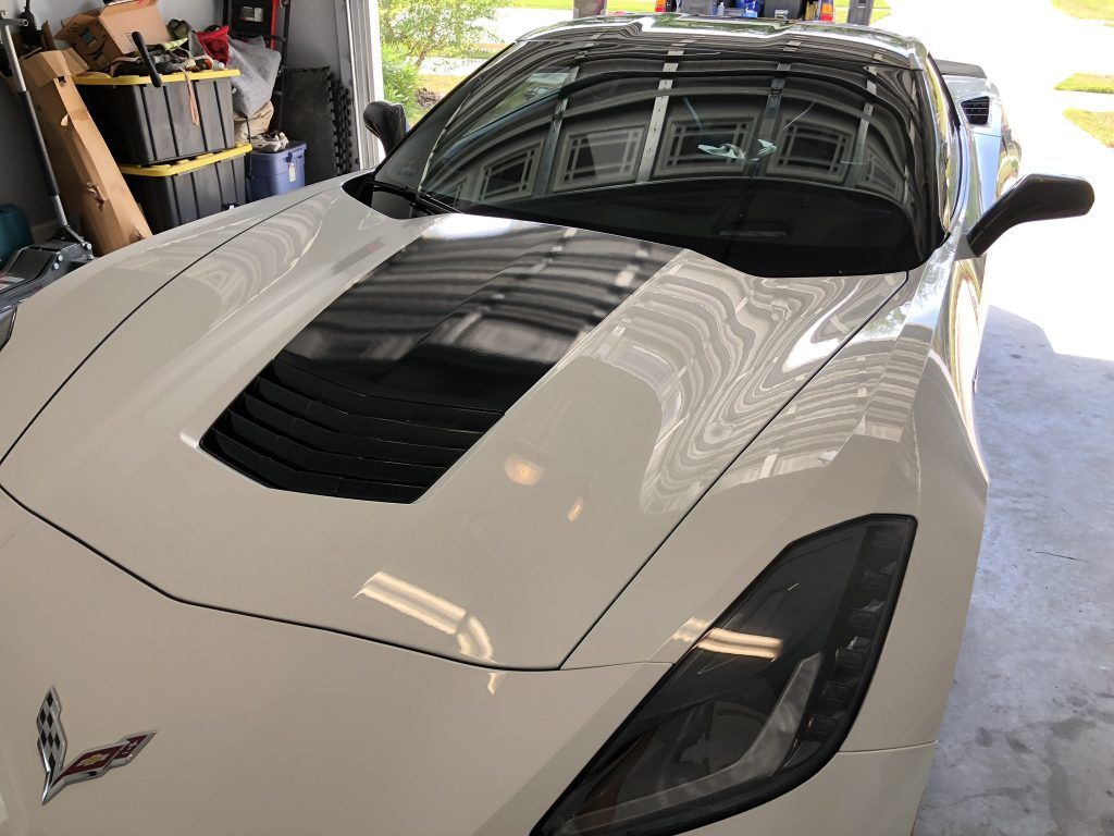A white sports car is parked in a garage.