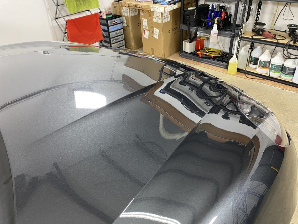 The hood of a car is sitting on a table in a garage.