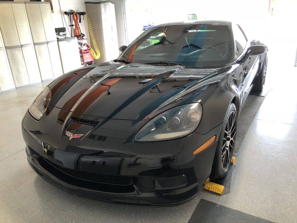 A black sports car is parked in a garage.