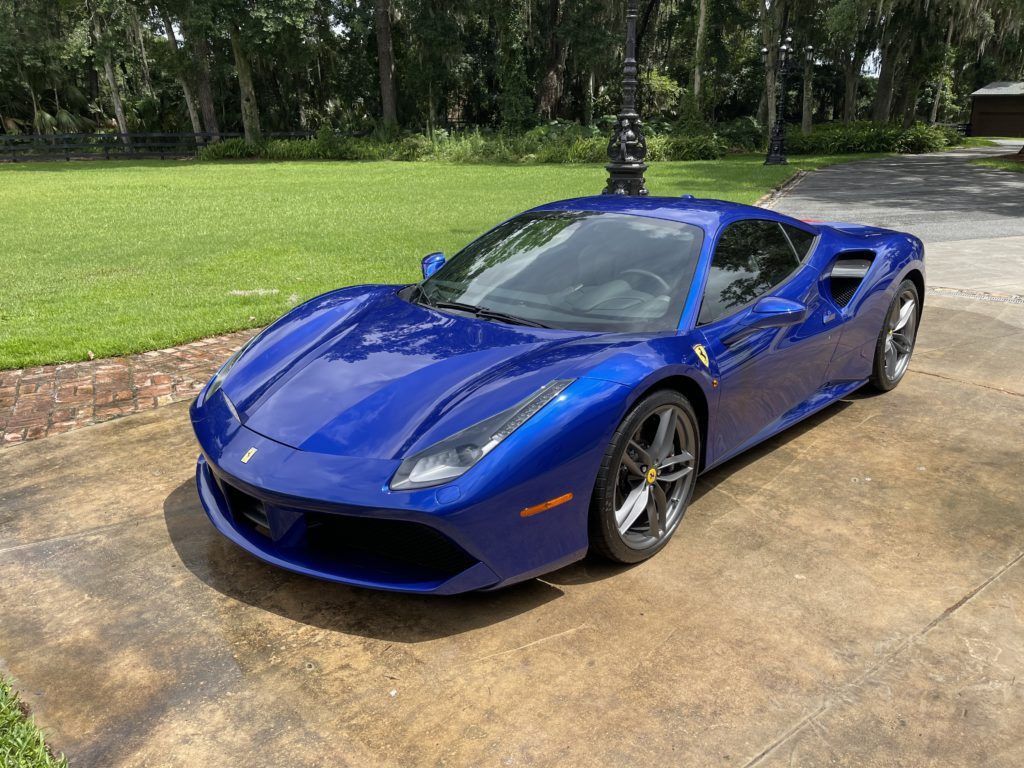 A blue ferrari 488 gtb is parked in a driveway.