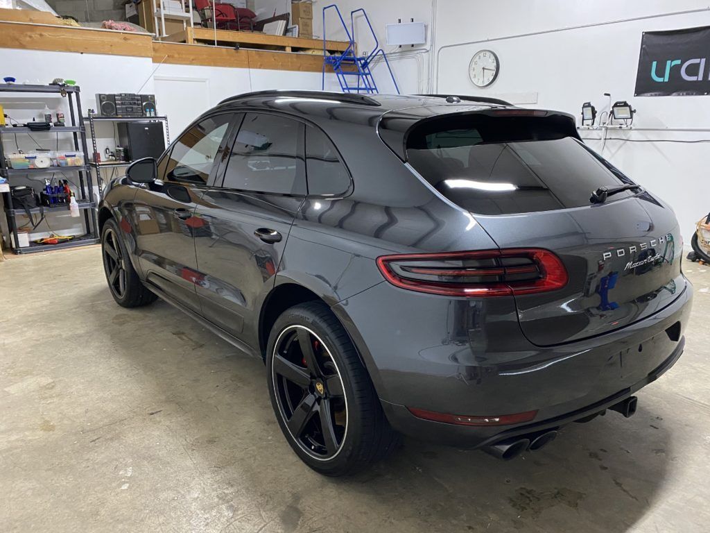 A gray porsche macan is parked in a garage.