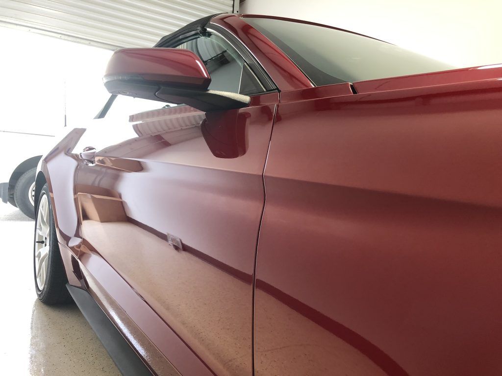 A red car is parked in a garage with the door open