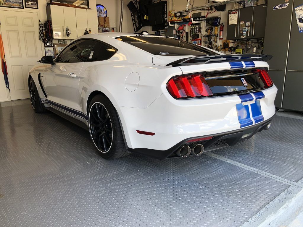 A white mustang is parked in a garage.