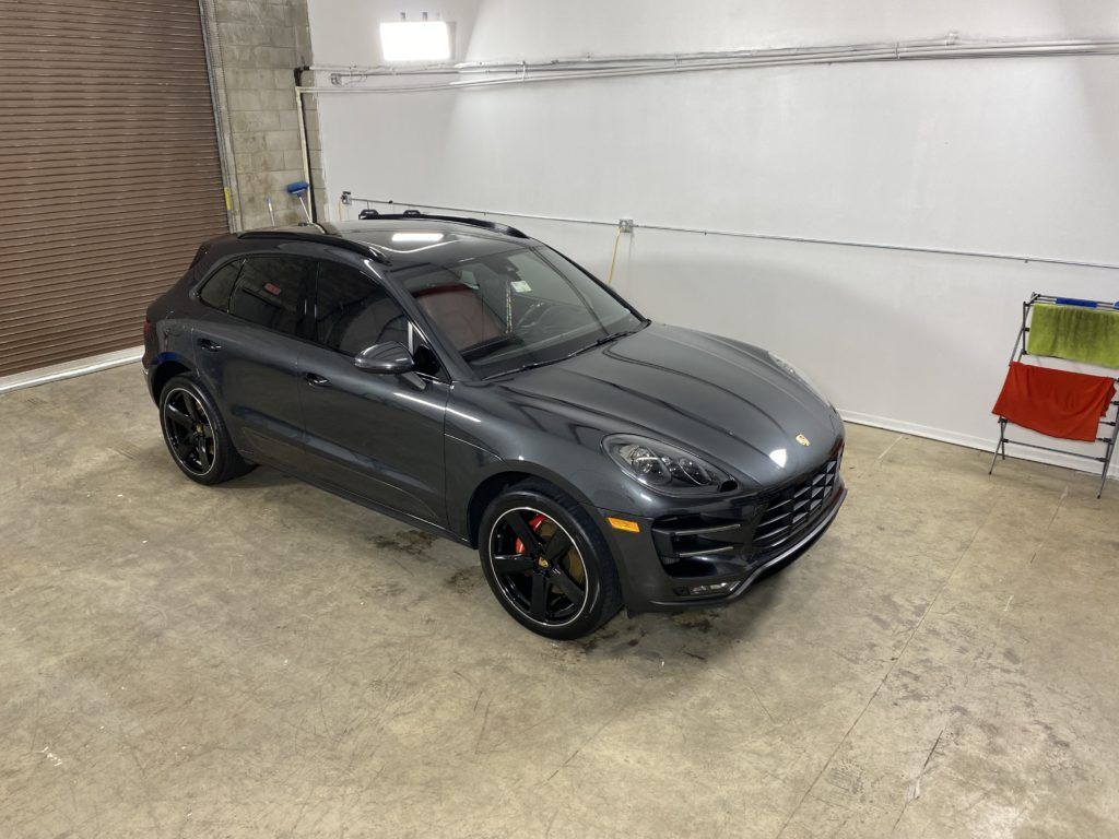 A gray porsche macan turbo is parked in a garage.