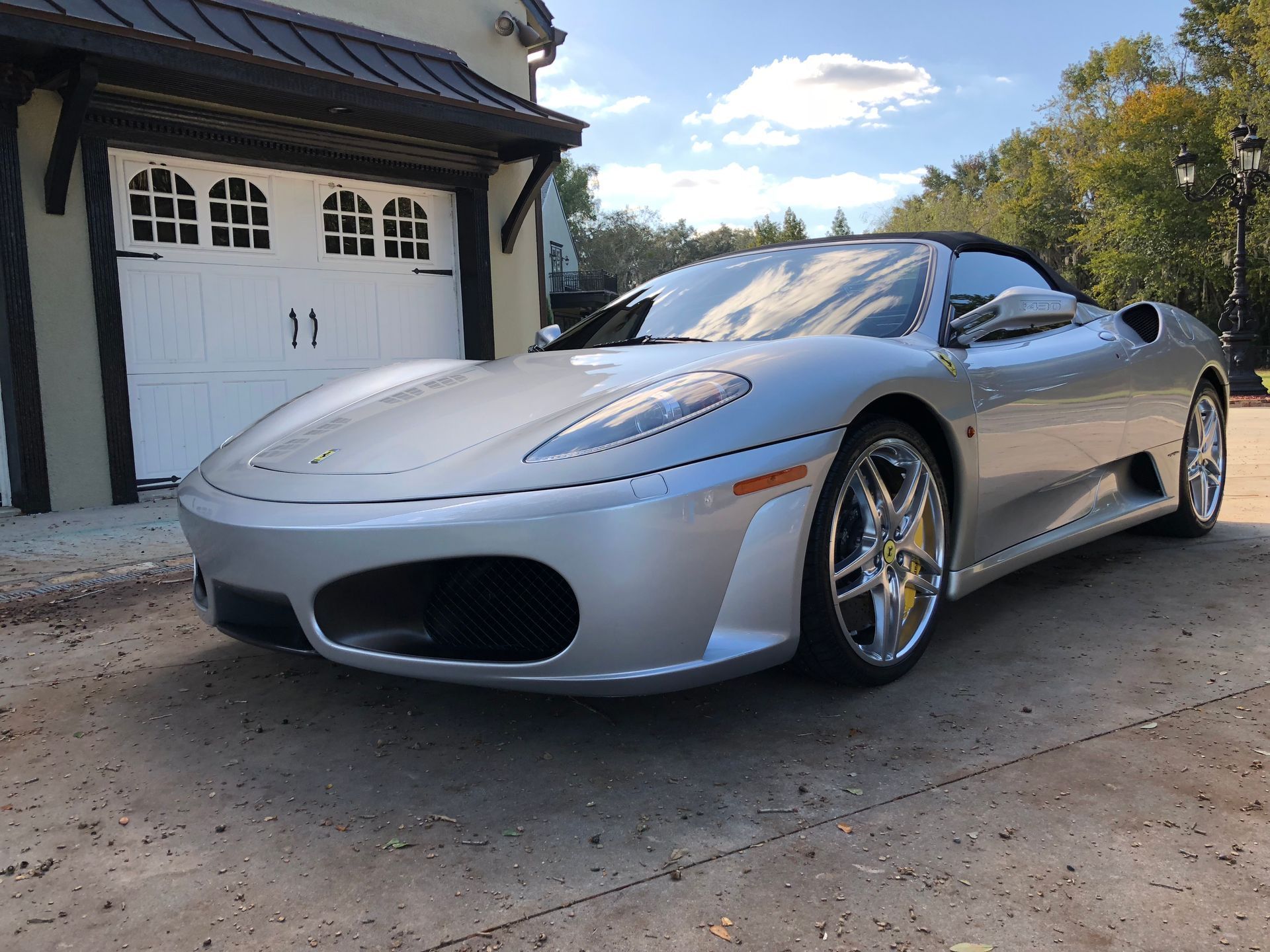 A silver sports car is parked in front of a garage.