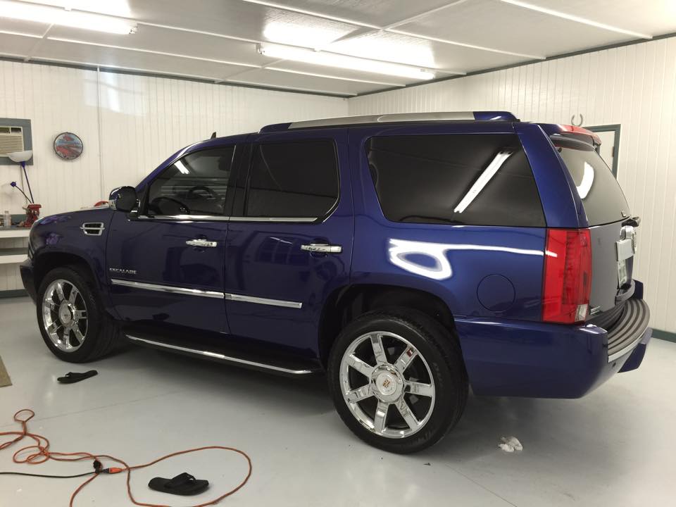 A blue cadillac escalade is parked in a garage