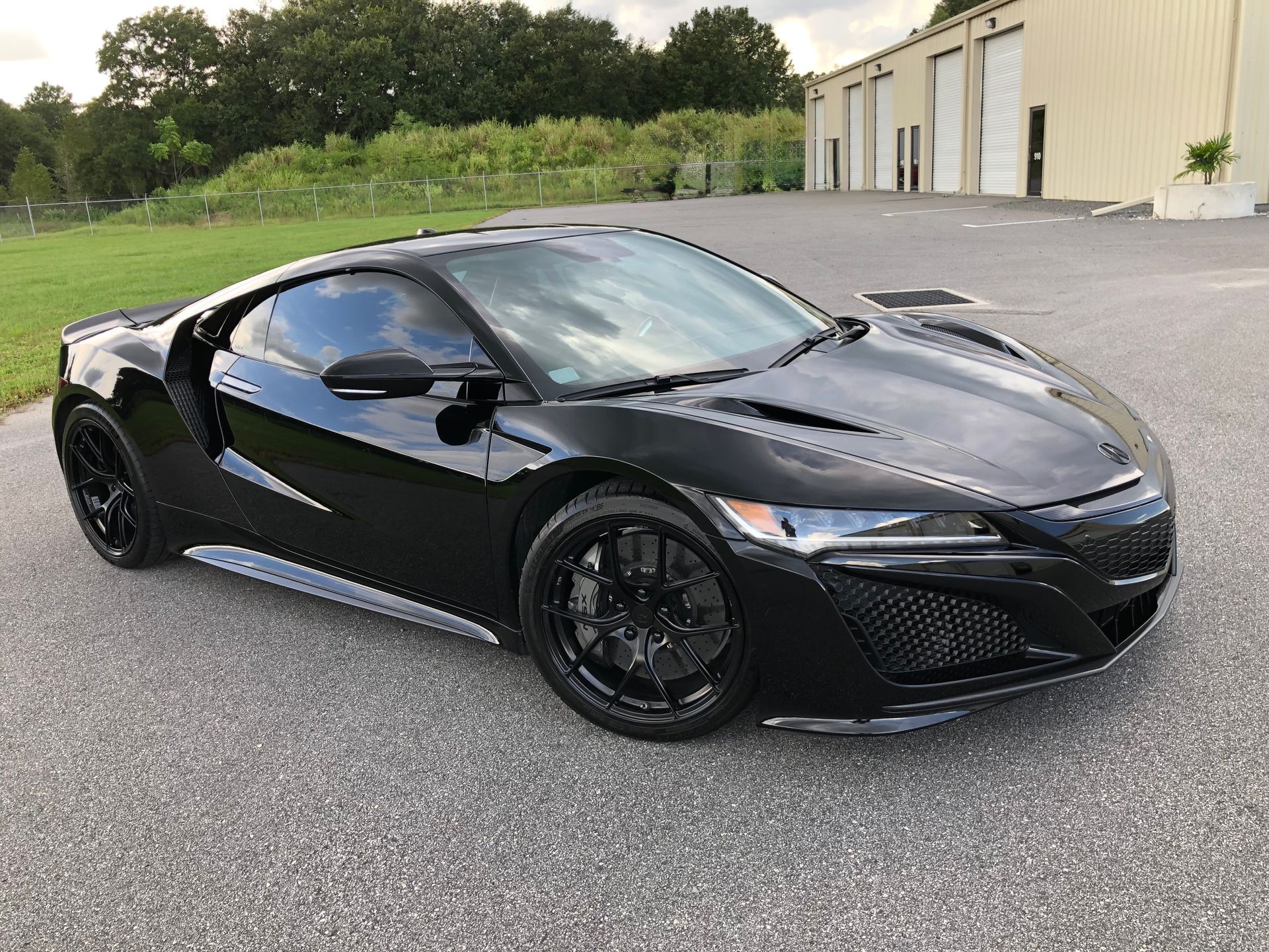 A black sports car is parked in a parking lot in front of a building.
