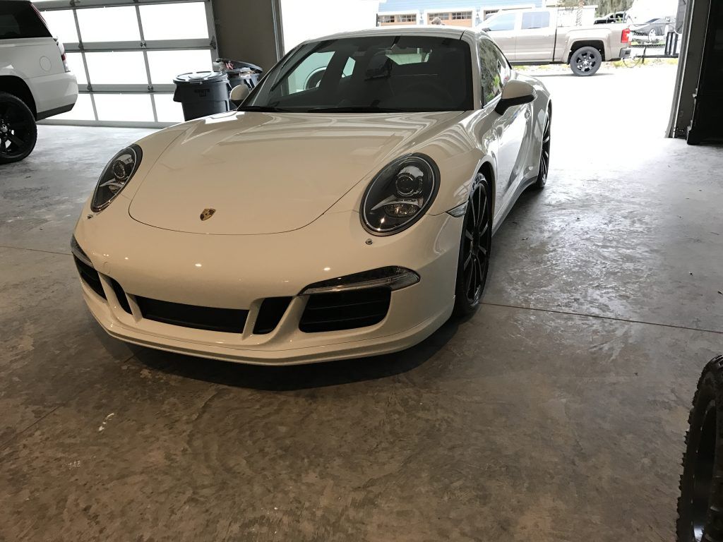 A white porsche 911 is parked in a garage.