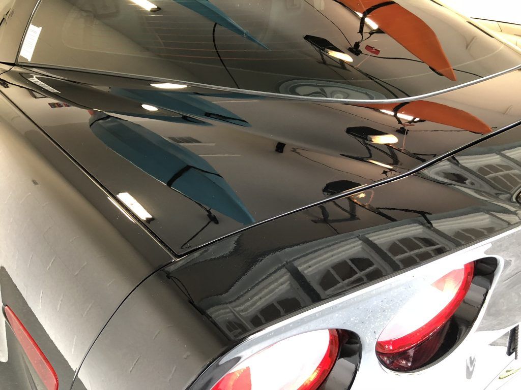 A close up of a car with a reflection of a building in the windshield.