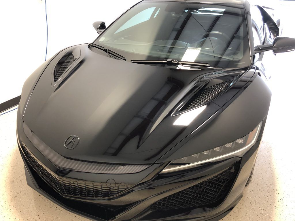 A black sports car is parked in a garage.