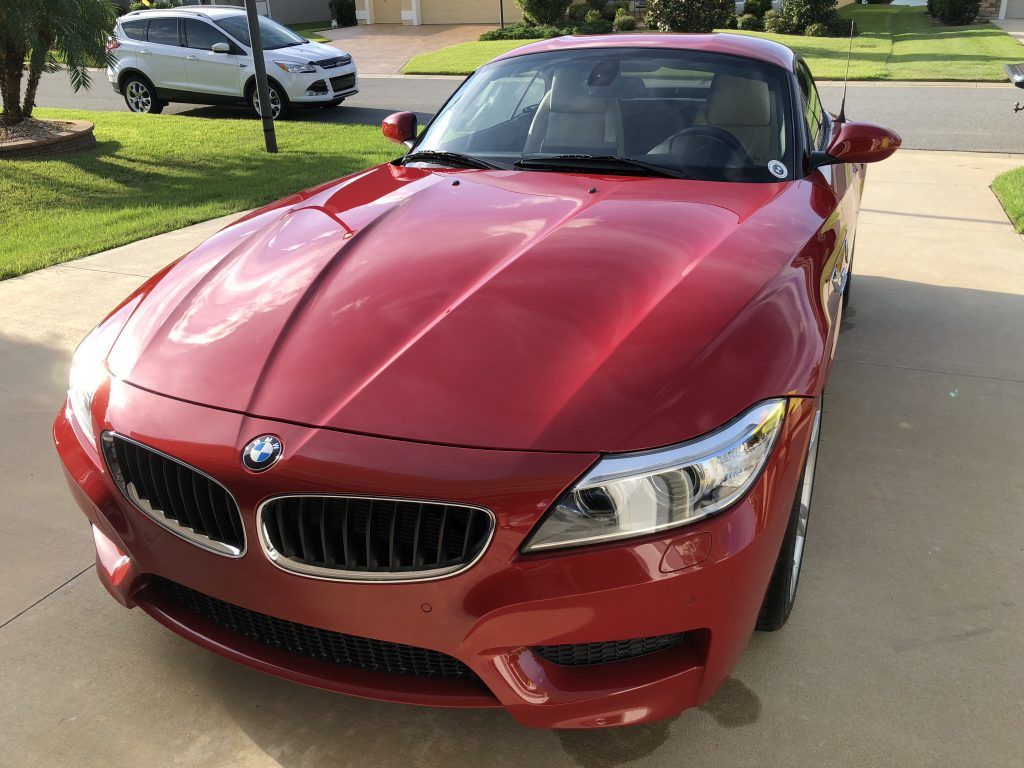 A red bmw z4 is parked in a driveway.
