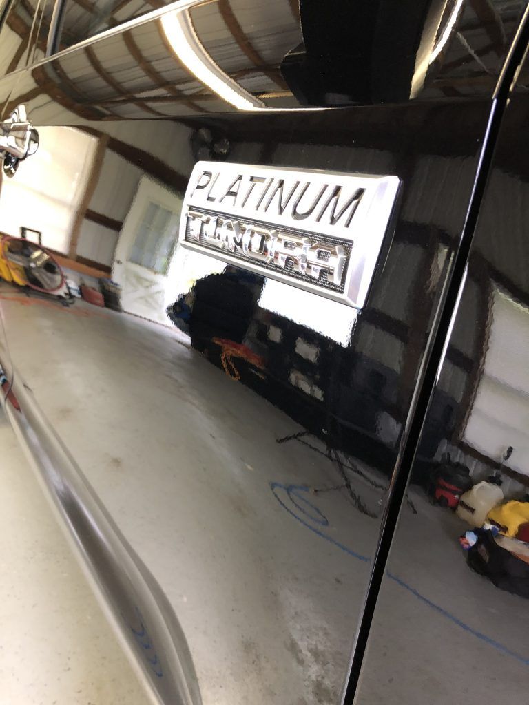 A black car with a platinum sticker on the side of it is parked in a garage.