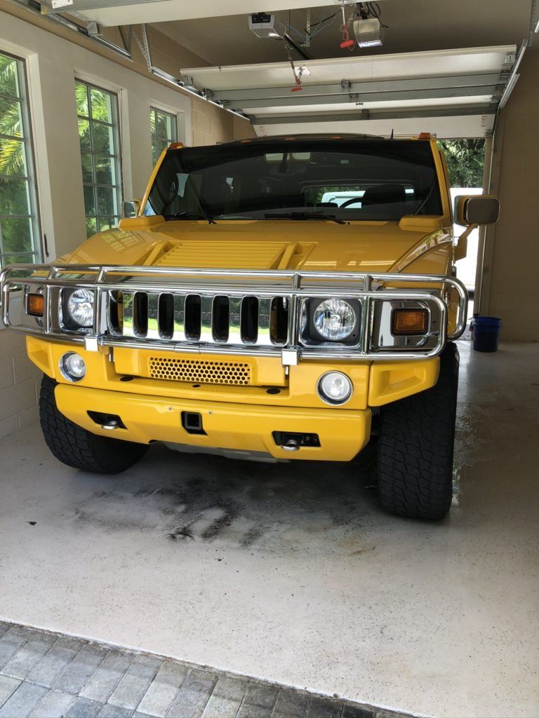 A yellow hummer is parked in a garage.
