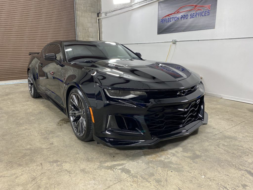 A black chevrolet camaro zl1 is parked in a garage.