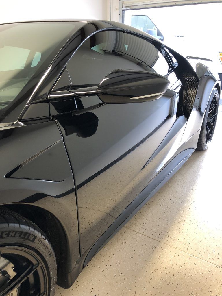 A black sports car is parked in a garage.