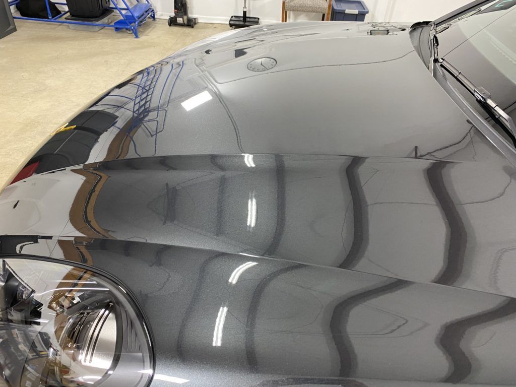 A close up of the hood of a black car in a garage.