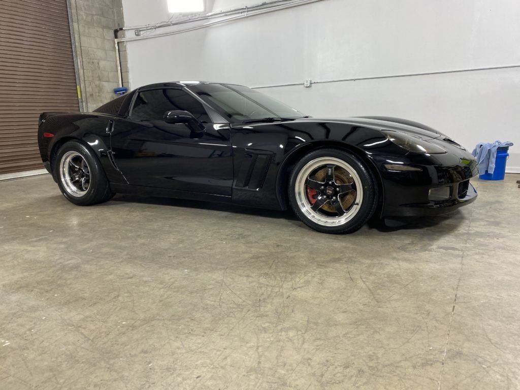 A black corvette is parked in a garage.