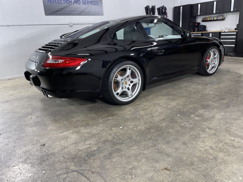 A black porsche 911 is parked in a garage.