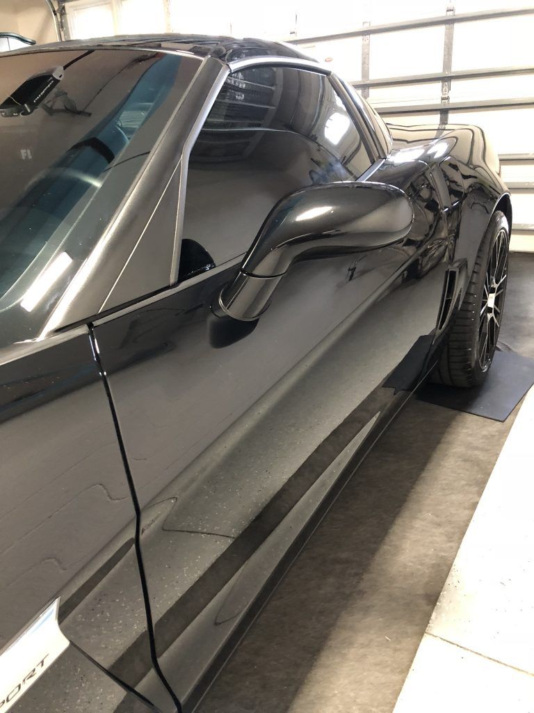 A black sports car is parked in a garage.