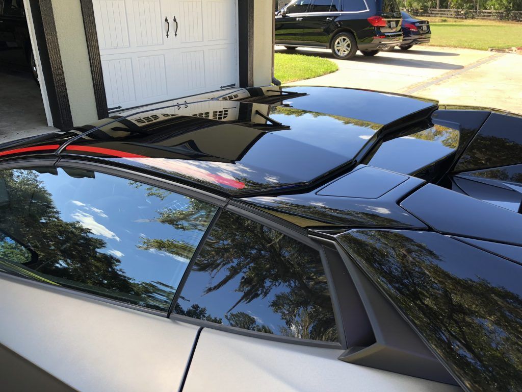 A black car is parked in front of a garage.