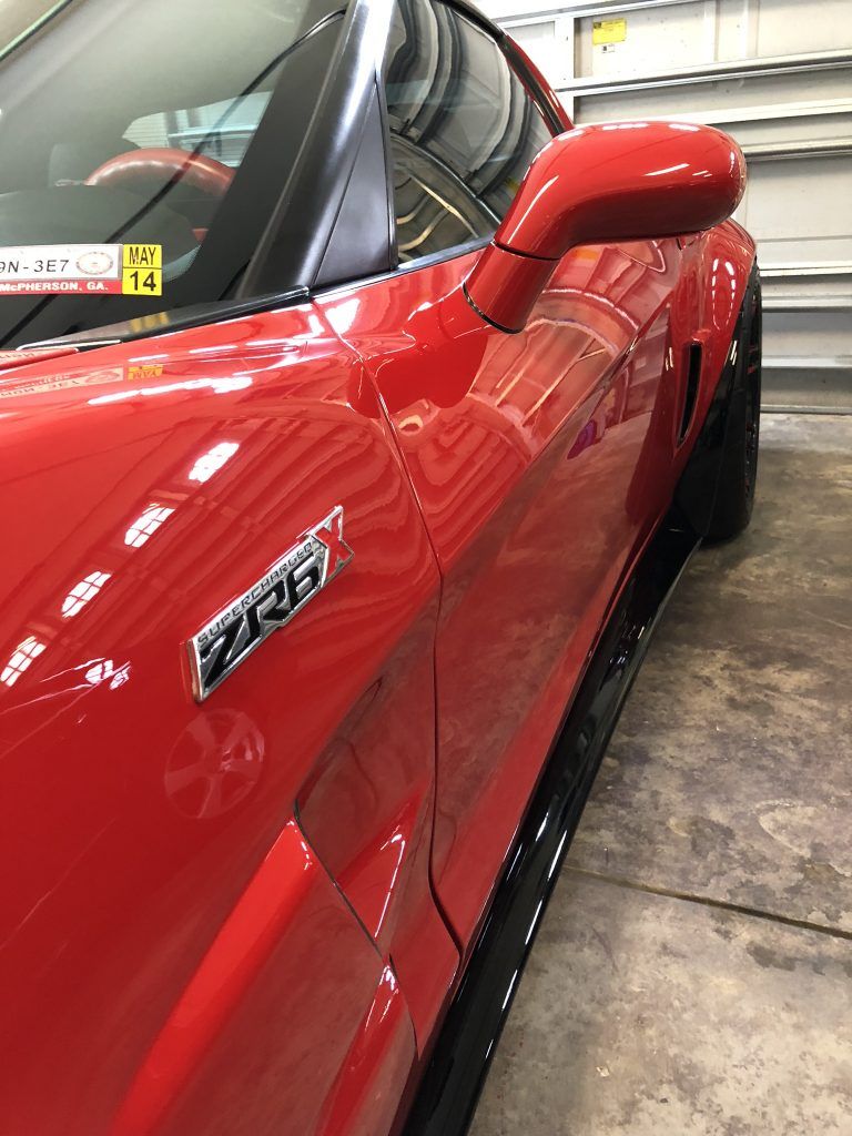 A red sports car is parked in a garage.