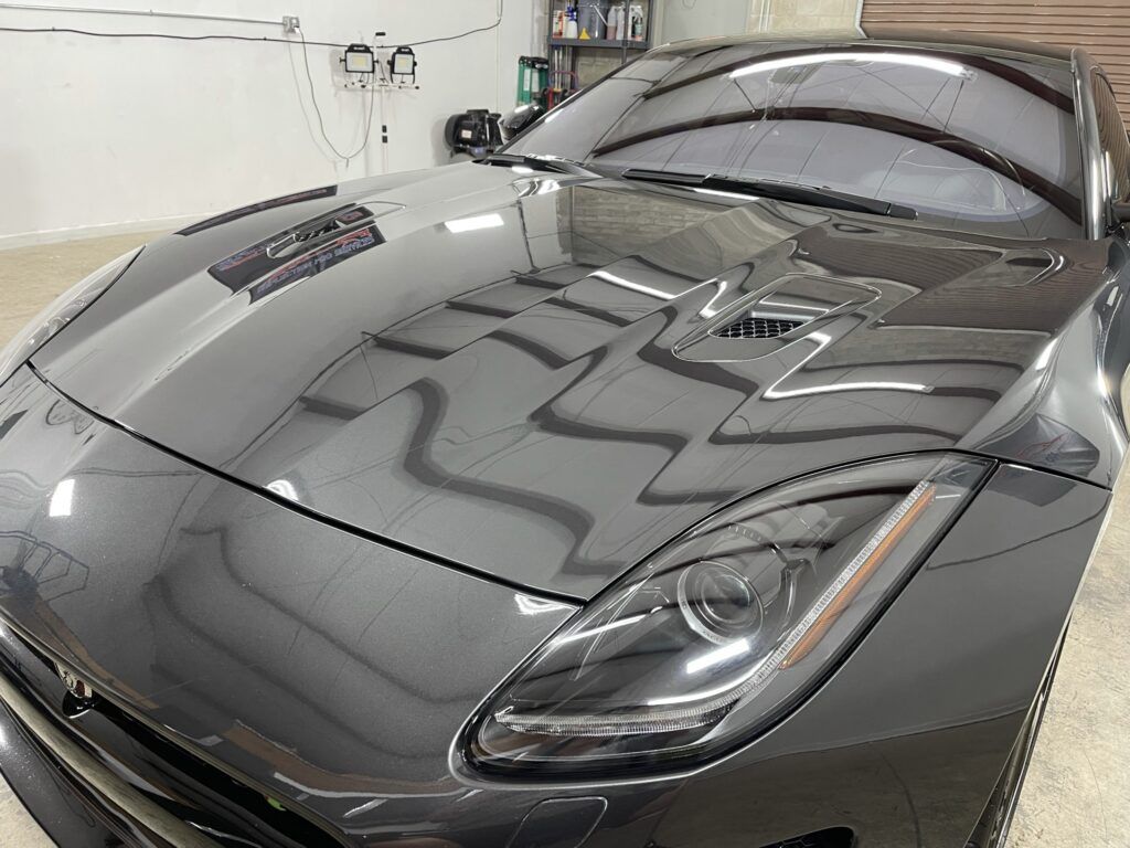 A black sports car is parked in a garage.