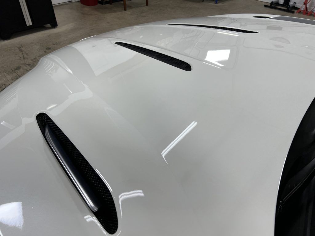 A close up of the hood of a white car in a garage.