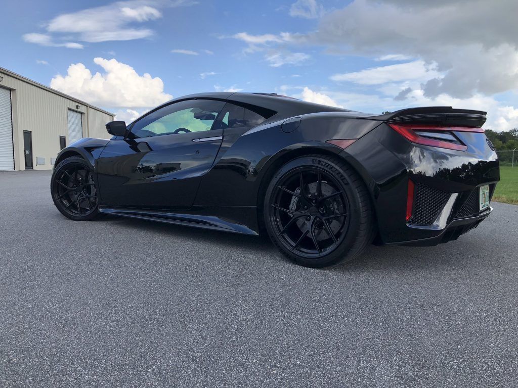A black sports car is parked on the side of the road in front of a building.