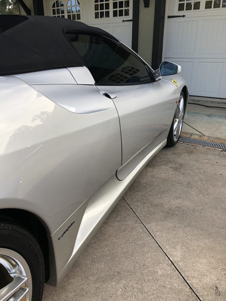 A silver sports car is parked in front of a garage door.
