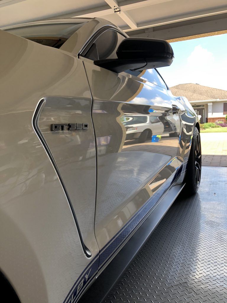 A white mustang is parked in a garage.