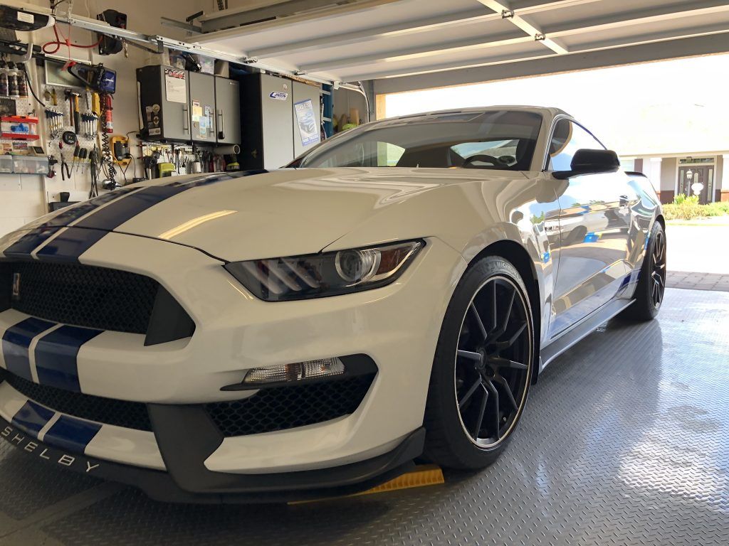 A white ford mustang is parked in a garage.