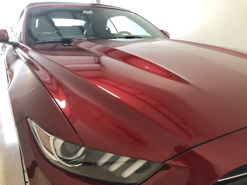 A red ford mustang is parked in a garage.