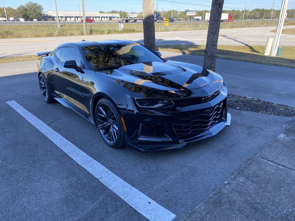 A black chevrolet camaro zl1 is parked in a parking lot.