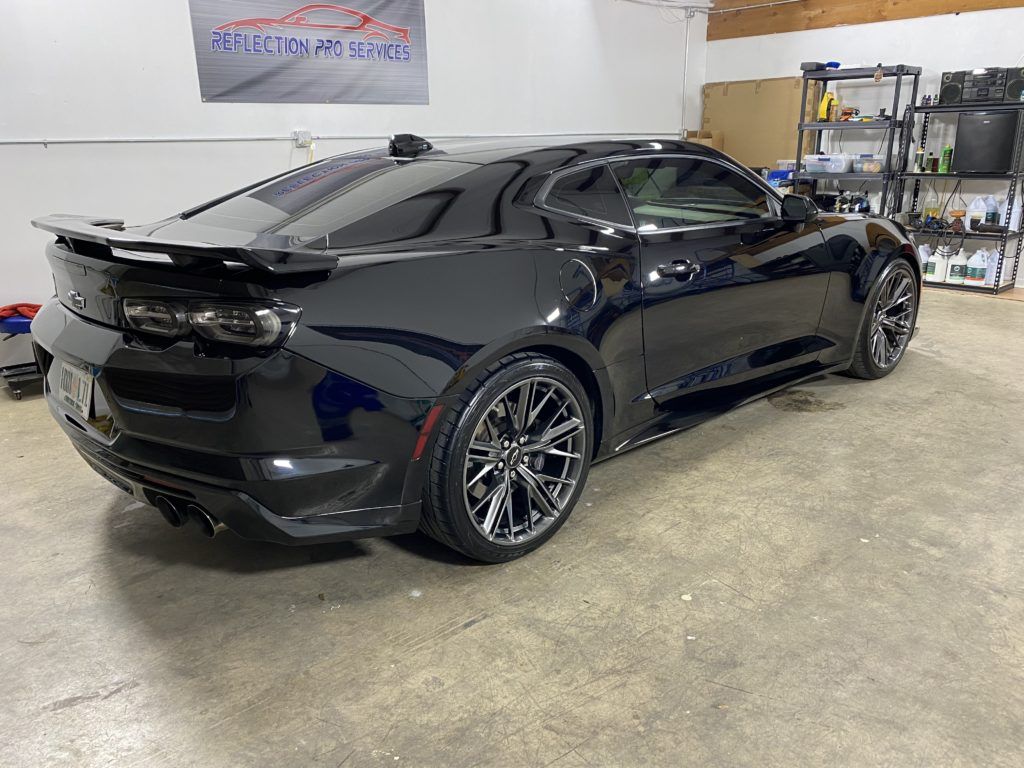 A black sports car is parked in a garage.