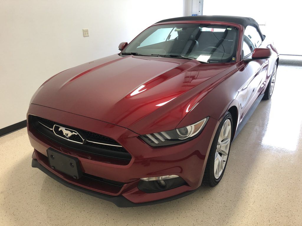 A red mustang convertible is parked in a garage.