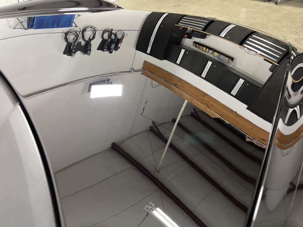 The inside of a boat with a reflection of a car in the mirror