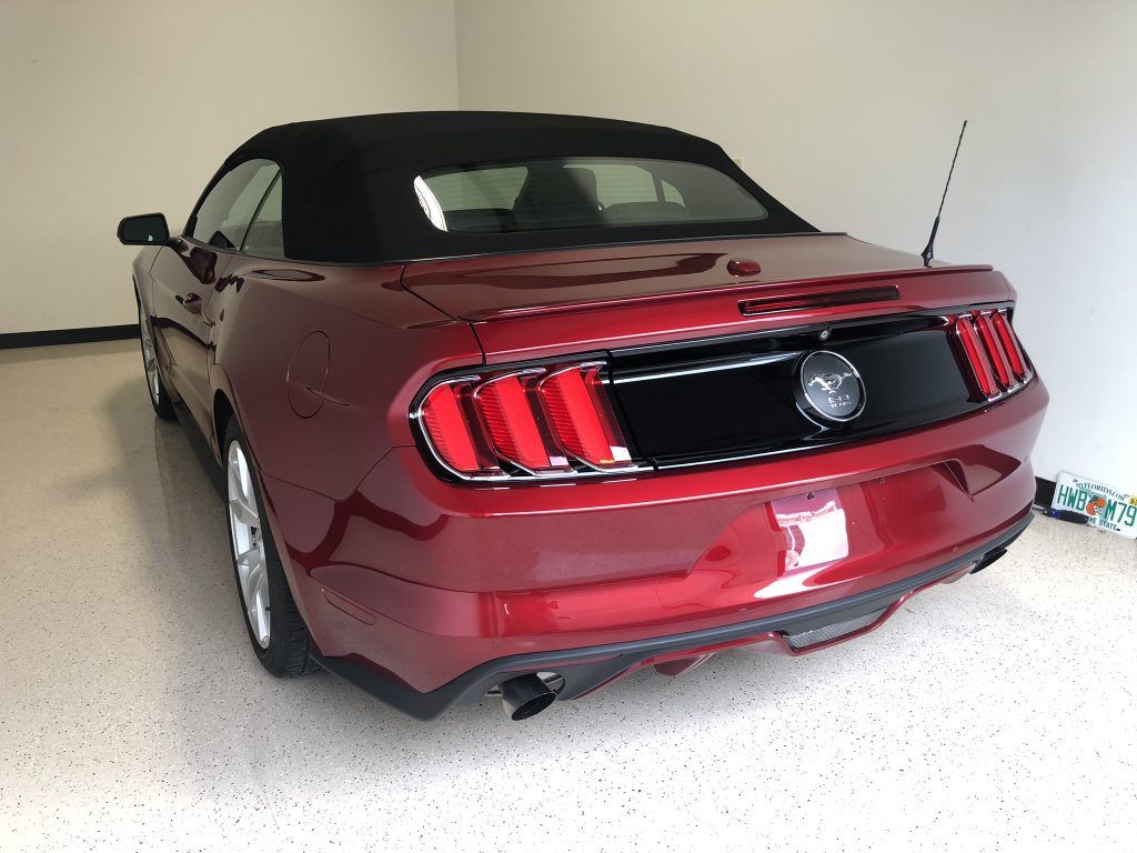 A red mustang convertible is parked in a garage.